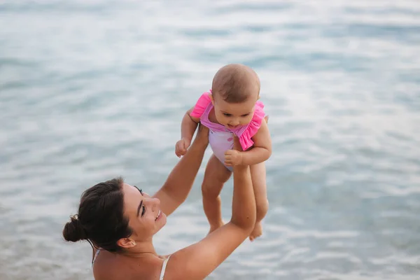 Vedere din spate a mamei se joacă cu fetița ei pe plajă. Contextul mării — Fotografie, imagine de stoc