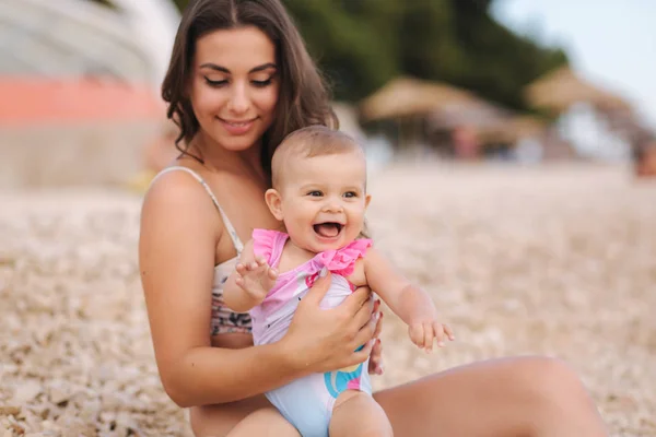 Portretul unei fetițe drăguțe cu mama ei pe plajă. Mama cu fiica în costum de baie lângă mare. Fericit copil — Fotografie, imagine de stoc