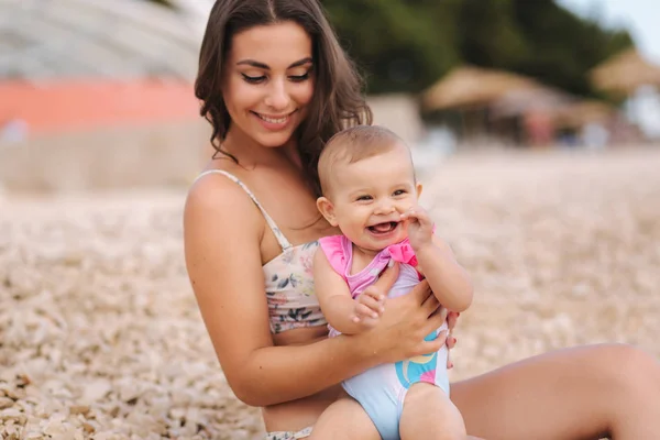 Portretul unei fetițe drăguțe cu mama ei pe plajă. Mama cu fiica în costum de baie lângă mare. Fericit copil — Fotografie, imagine de stoc