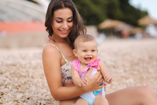 Portretul unei fetițe drăguțe cu mama ei pe plajă. Mama cu fiica în costum de baie lângă mare. Fericit copil — Fotografie, imagine de stoc