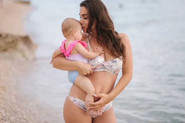 Portretul mamei ține fetița pe mîini pe plaja din mare. Mama si fiica in costum de baie — Fotografie, imagine de stoc