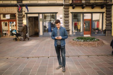 Şehrin merkezinde genç şık adam stand. Adam kablosuz kulaklıklar kullanmak