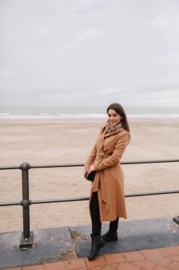 Kuzey Denizi boyunca güzel ceket ayakta makyaj ile şık bayan. Kadın gülümseme