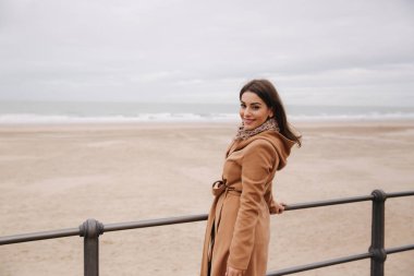 Kuzey Denizi boyunca güzel ceket ayakta makyaj ile şık bayan. Kadın gülümseme