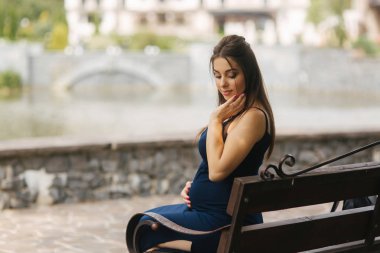 Gölü yakınındaki bir bankta oturan hamile kadın. Altı aylık hamilelik