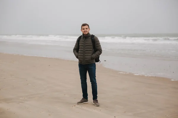 Promenade touristique masculine le long de la mer du Nord. Homme avec sac à dos debout sur la côte par temps pluvieux. Belle mer — Photo