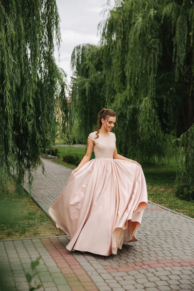 Fashionable girl spin around in park. Evening dress — Stock Photo, Image