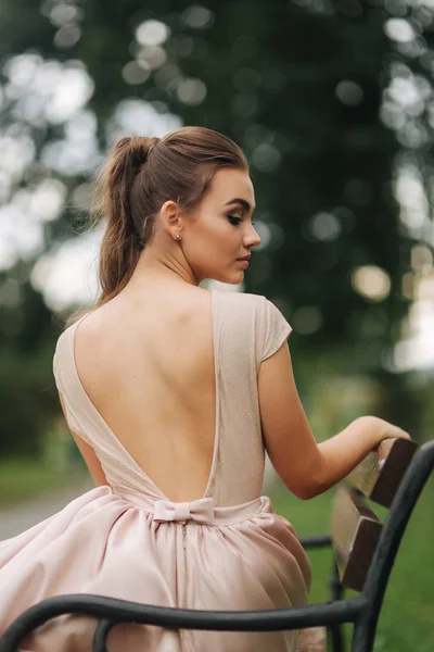 Elegante modelo glamoorus se sienta en el banco en vestido de noche — Foto de Stock