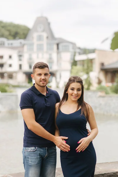 Těhotná žena a její husbant objetí navzájem a úsměv. Muž položil ruku na břicho těhotné ženy. Šest měsíců těhotenství — Stock fotografie