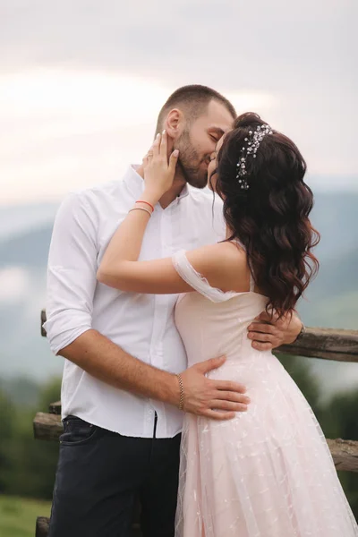 A noiva encantadora abraça o seu belo noivo nas montanhas. Caminhada de casal de casamento bonita. Gackground verde — Fotografia de Stock