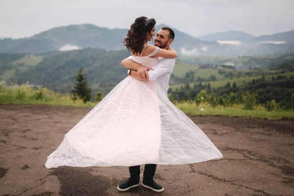 Beautiful wedding couple in Carpathian mountains. Handsome man with attractive woman. Bride spin around