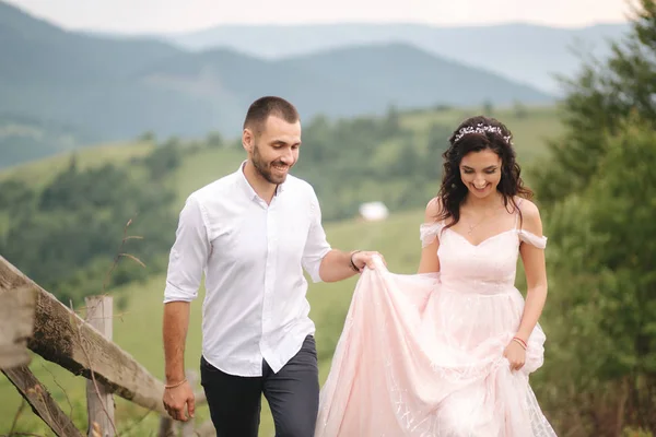 Krásný mladý svatební pár, stojící na zeleném svahu, kopec. Ženich a nevěsta v Karpatských horách — Stock fotografie