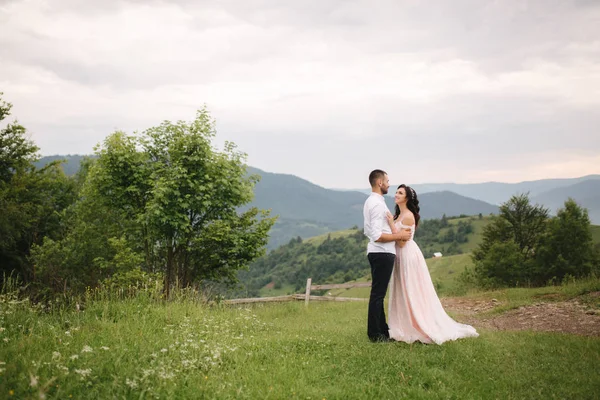 Gyönyörű fiatal esküvő pár állva a zöld lejtőn, dombon. Vőlegény és menyasszony a Kárpátokban — Stock Fotó