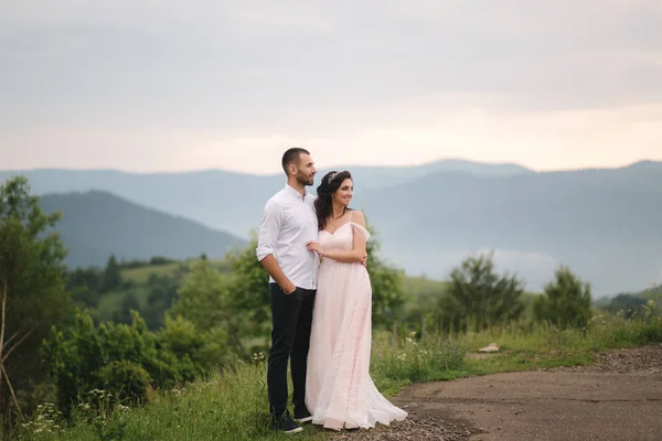 Gyönyörű fiatal esküvő pár állva a zöld lejtőn, dombon. Vőlegény és menyasszony a Kárpátokban — Stock Fotó