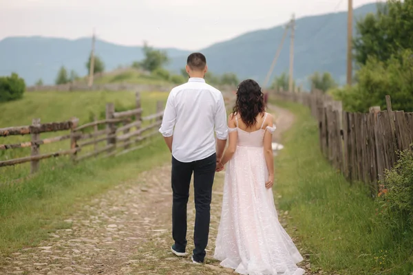 Um homem bonito leva a noiva a belas montanhas dos Cárpatos. Casal feliz. Visão traseira — Fotografia de Stock