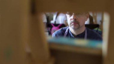 Gözlük yetişkin erkek sanatçı fırça ve yağlı boya kullanarak bir resim boyama. Sanat konsepti. Yaratıcı mutlu ressam renkli bir resim çizer. Çizim stüdyosu