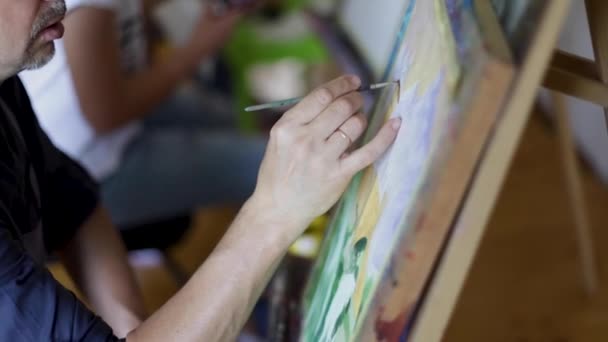 アーティストは油絵ブラシの絵を描きます。男性アーティストの手にブラシ。アートコンセプト。絵画のクローズアップ — ストック動画