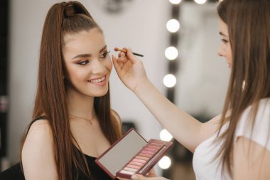 Güzellik stüdyosunda makyaj sanatçısı çalışması. Profesyonel tarafından başvuran kadın Master makyaj. Güzel makyaj sanatçı çiller ile Redhead modeli için bir makyaj yapmak. O bir palet kullanmak