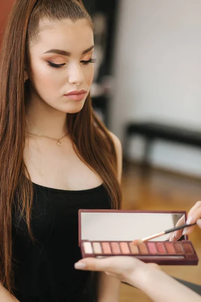 Trabajo de artista de maquillaje en su estudio de belleza. Mujer aplicando por profesional maquillaje maestro. Hermoso maquillaje artista hacer un maquillaje para modelo pelirroja con pecas. Usa una paleta. — Foto de Stock