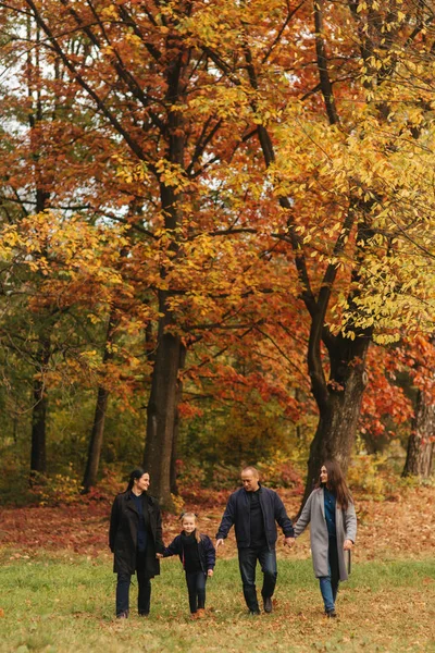 一家人在秋天的森林里走着, 落叶也在落叶。母亲的父亲和两个女儿在公园里 — 图库照片