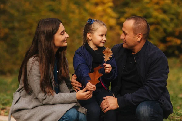 父亲和两个女儿在森林里。秋天的天气和五颜六色的背景。幸福的家庭。两个妹妹向爸爸示爱 — 图库照片