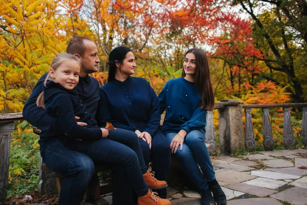 Portrait of happy family sitting on the bench in the forest. Autumn weather and colorful trees — Stock Photo, Image