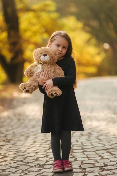 手里拿着泰迪熊的小女孩的肖像。公园里快乐的孩子。美丽的女孩模型微笑对照相机 — 图库照片