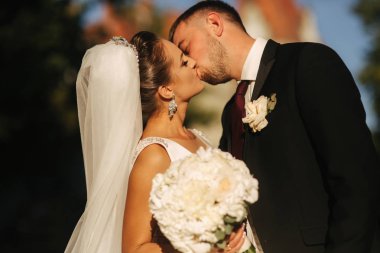Damat ve gelin kalenin önünde duruyorlar. Kadın elinde beyaz çiçek buketi tutun. Erkek öpücük kadın yakın çekim