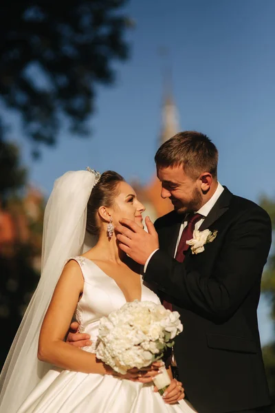 Groom and bride are standing in front of castle. Woman hold bouquet of white flower in hands — Stock Photo, Image