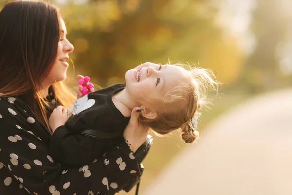 Moeder en kleine dochter wandelen in de herfst weer. Stijlvolle kleine dochter en haar mooie moeder. Gelukkige kindertijd. Buiten portret van gelukkige familie. Veel plezier — Stockfoto