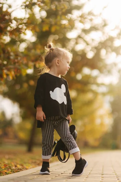 Gelukkig klein meisje wandelen in het Park in de herfst. Mooie vrouwelijke Kid op gele achtergrond — Stockfoto