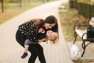 Anne ve küçük kızı sonbahar havasında yürüyorlar. Şık küçük kızı ve onun güzel annesi. Mutlu çocukluk. Mutlu bir ailenin açık hava portresi. İyi eğlenceler