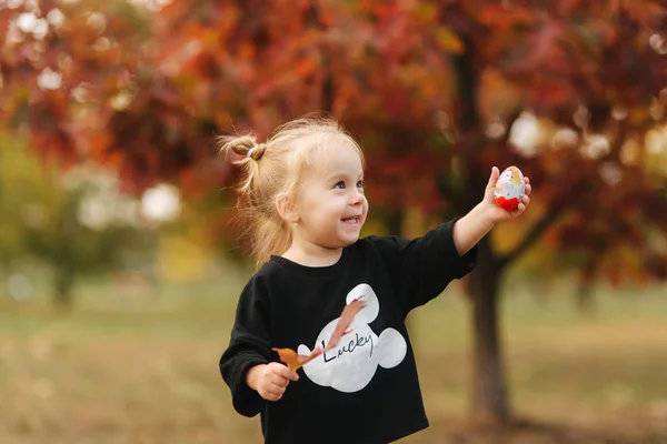 Ευτυχισμένο κοριτσάκι που περπατάει στο πάρκο το φθινόπωρο. Όμορφο θηλυκό παιδί σε κίτρινο φόντο — Φωτογραφία Αρχείου