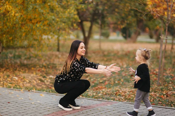 Mom and daughter spend time together in the park in autumn time. Happy family concept