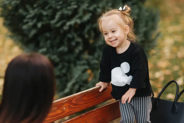 Mom and daughter spend time together in the park in autumn time. Happy family concept