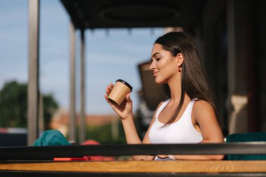 Çekici kız bir zanaat fincan kafenin terasında kahve dring. Güzel esmer