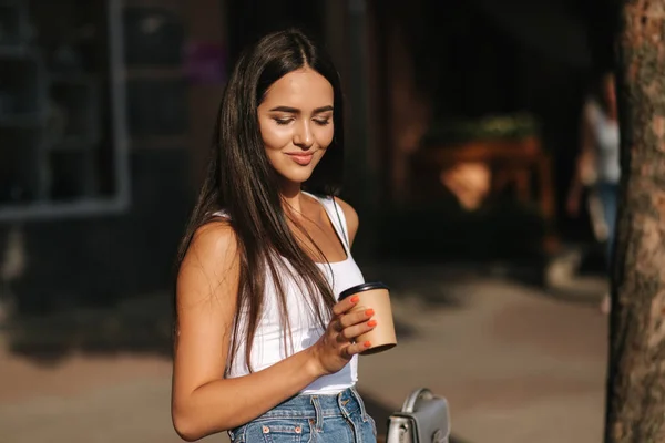 Aantrekkelijk meisje dring koffie op het terras van het café van een ambachtelijke Cup. Mooie brunette — Stockfoto