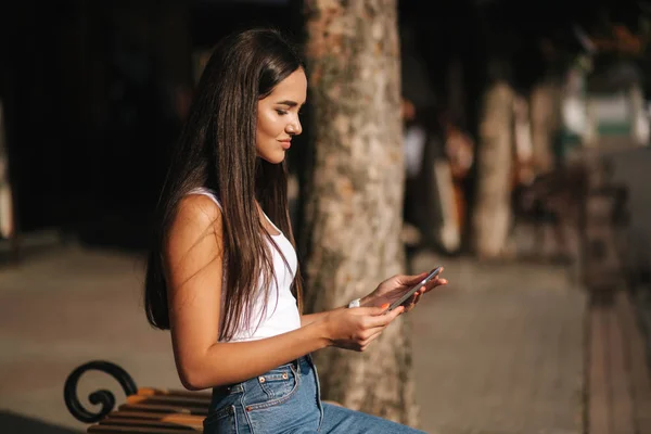 Hermosa chica utilizar la tableta fuera. Mujer sentada en el banco. Día caliente de verano — Foto de Stock