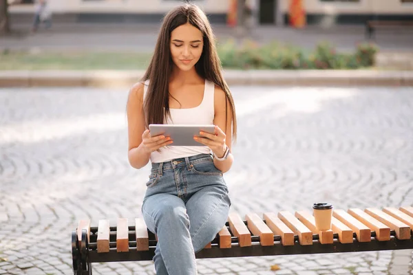 Όμορφο κορίτσι χρησιμοποιούν tablet έξω. Γυναίκα που κάθεται στον πάγκο. Ζεστή καλοκαιρινή μέρα — Φωτογραφία Αρχείου