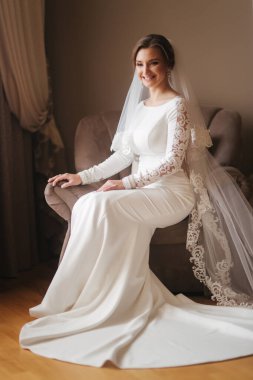 Evde sandalyede oturan muhteşem gelin. Gelinlik güzel kadın