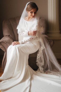 Evde sandalyede oturan muhteşem gelin. Gelinlik güzel kadın