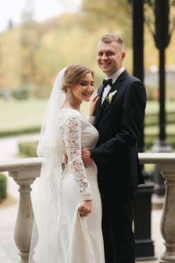 Balkonda duran güzel bir çiftin portresi. Dışarıda sonbahar havasında şık gelin ve damat. Mutlu aile