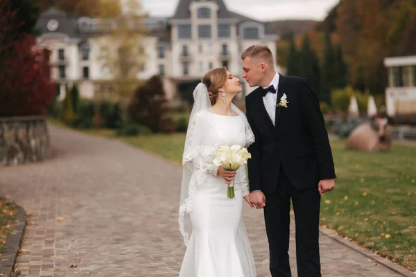 Casal elegante andando no parque no dia do casamento. Felizes recém-casados lá fora no Outono. Fundo de folhas amarelas e vermelhas — Fotografia de Stock