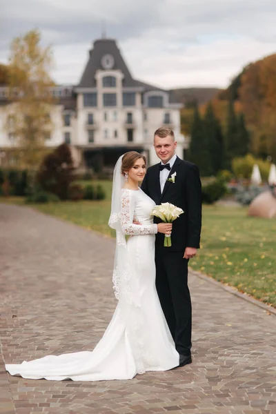 Casal elegante andando no parque no dia do casamento. Felizes recém-casados lá fora no Outono. Fundo de folhas amarelas e vermelhas — Fotografia de Stock