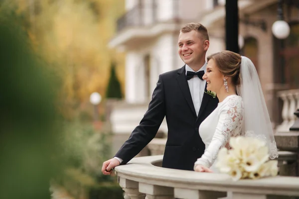 美丽的婚礼夫妇的画像站在阳台上. 外面的秋天里,新郎和新娘都很时髦. 快乐的家庭 — 图库照片