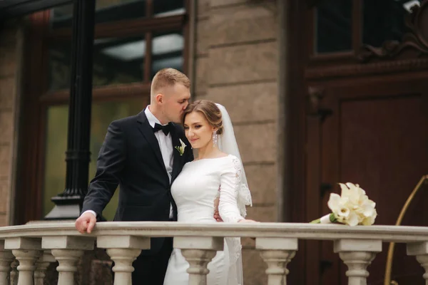 Portret pięknej pary weselnej stoi na balkonie. Stylowa panna młoda i pan młody w jesiennej pogodzie na zewnątrz. Szczęśliwa rodzina — Zdjęcie stockowe