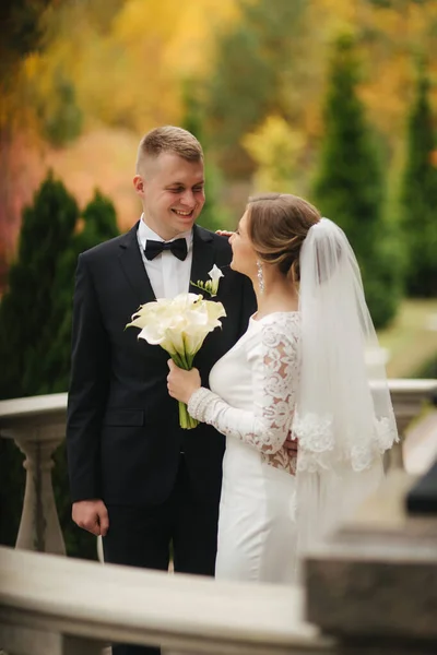 Πορτρέτο του όμορφου ζευγαριού σταθεί στο μπαλκόνι. Κομψή νύφη και γαμπρός σε φθινοπωρινό καιρό έξω. Ευτυχισμένη οικογένεια — Φωτογραφία Αρχείου