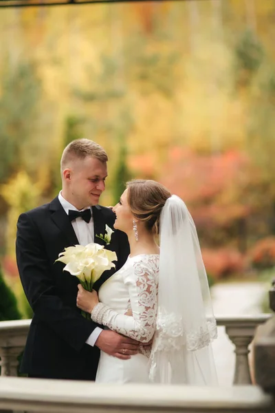 Porträtt av vackra bröllopspar står på balkongen. Snygg brud och brudgum i höstväder utanför. Lycklig familj — Stockfoto