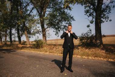 Parkta yürüyen genç adam. Siyah elbiseli yakışıklı damat