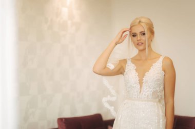 Genç ve güzel gelini evde. Sarı saçlı kız gelinlik